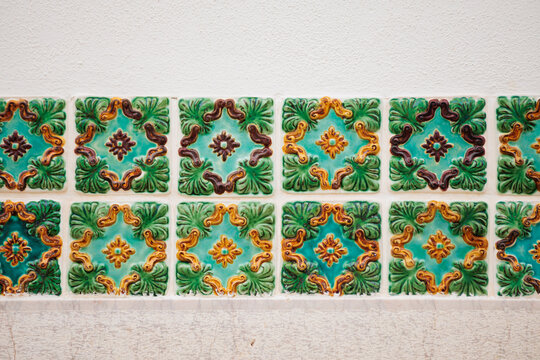 Mosaic of floral pattern of tiles in vintage style with squared shapes and copy space in a sand wall