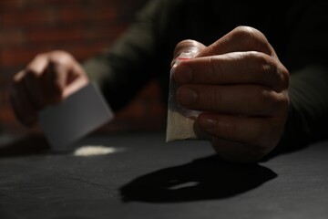 Addicted man with hard drug and blank card preparing for consumption at grey table, selective focus