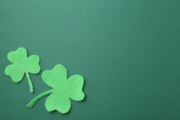 St. Patrick's day. Decorative clover leaves on green background, flat lay. Space for text