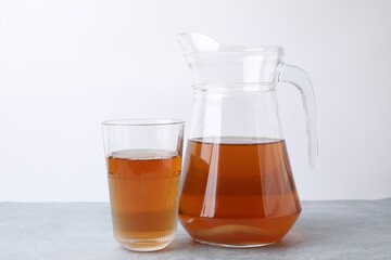 Homemade fermented kombucha in glass and jug on light grey table