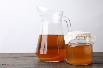 Homemade fermented kombucha in glass jar and jug on wooden table. Space for text