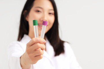 Asian woman holding empty test tubes on white background, closeup