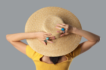 Young woman with beautiful rings and hat on grey background