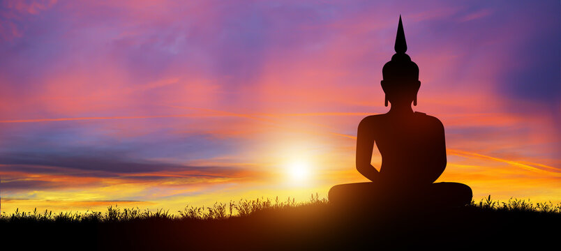 Silhouette of Buddha mediating in the twilight with sunrise background. Buddhist holiday Concept.