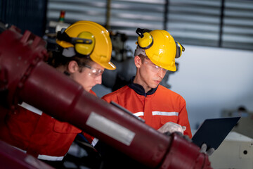 group of male engineer workers maintenance automatic robotic arm machine in a dark room factory. worker checking and repairing automatic robot hand machine. Worker wearing safety glasses and helmet.