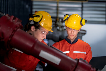 group of male engineer workers maintenance automatic robotic arm machine in a dark room factory. worker checking and repairing automatic robot hand machine. Worker wearing safety glasses and helmet.