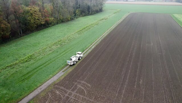 High Resolution Video of a Vibro-Truck shot with a drone. It shows the truck driving over a field, with the drone following its path.