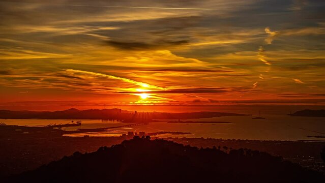 San Francisco Bay as seen from the Oakland side of the harbor during a golden sunset - time lapse cloudscape