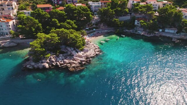 Brela Punta Rata Beach gleams with activity against a mountain backdrop. Boats dot clear sea waters in summer Croatia. Popular tourist destination.