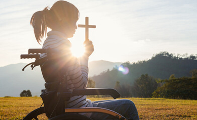 Christian, Christianity, Religion copy space background. Silhouette girl in wheelchair praying and...