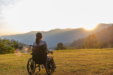 Silhouette Girl in wheelchair looking sunset mountain background. - obrazy, fototapety, plakaty