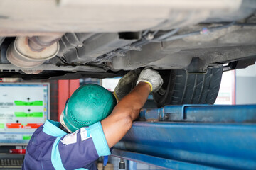 Auto mechanic working on a car in auto repair shop.Car mechanic tightens suspension adjustment...