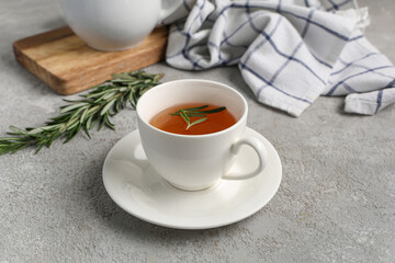 Cup of hot rosemary tea on grey background