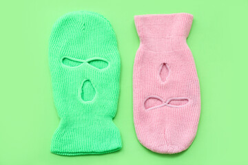 Stylish balaclavas on green background