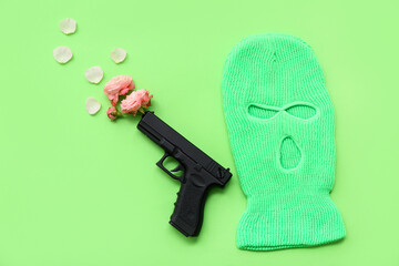 Stylish balaclava with roses and gun on green background