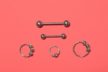 Stylish barbells and rings for piercing on red background