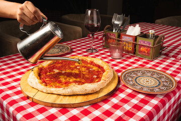 person adding oil to a pizza