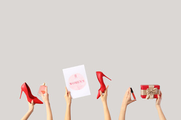 Female hands with festive postcard, gift box and high heel shoes on white background. International...