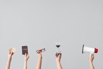 Female hands holding hourglass, megaphone, law book and money on grey background