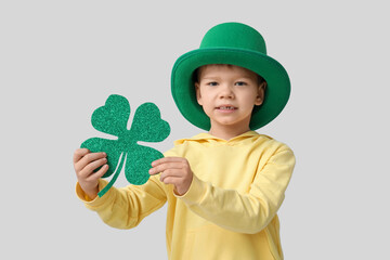Cute little boy in leprechaun hat with clover on grey background. St. Patrick's Day celebration