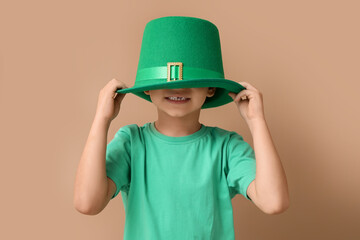 Cute little boy in leprechaun hat on brown background. St. Patrick's Day celebration
