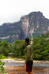 Naklejka premium young adult person pointing to Angel Falls in Canaima National Park, Venezuela