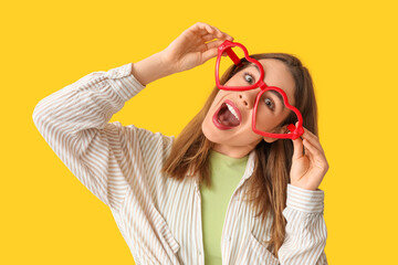 Beautiful young happy woman in funny disguise on yellow background. April Fools Day celebration