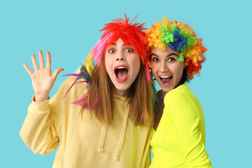 Beautiful young shocked women in funny clown disguise on blue background. April Fools Day...