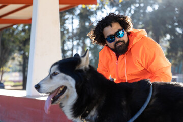 Young man with curly hair and sunglasses with his husky dog in a park in Mexico City