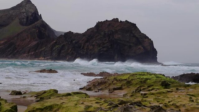 Turbulent and  agitated wave currents on sand beach with sea water rocks with an islet in the background, 50fps Porto Santo Island