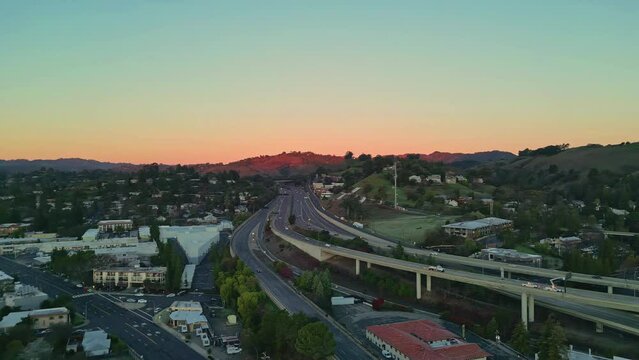 Aerial drone shot over downtown Walnut Creek, with the BART and highway 680 surrounded by houses in California, USA during evening time.