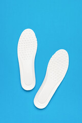 Two bright white insoles on a blue background.