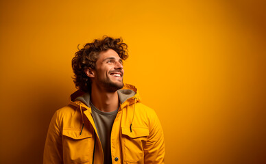 Fototapeta na wymiar young man dressed in yellow looks to the side happy and smiling. scene with text space with yellow background
