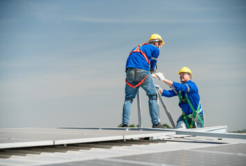 Male technicians holding solar panels on factory roofs and Engineers in helmets are helping each...