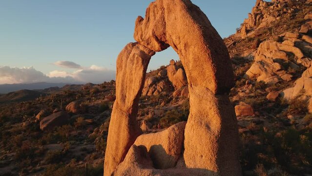 Sunset flight through rock arch in Arizona cactus hills