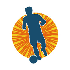 Silhouette of a male soccer player kicking a ball. Silhouette of a football player in action pose.