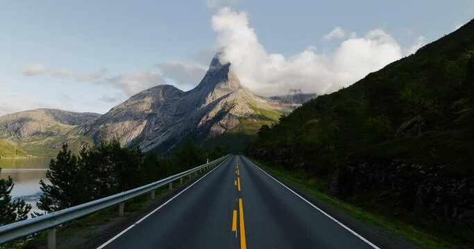 Empty asphalt road leads to epic morning view of majestic Stetind Norway