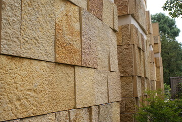 Corner view of a modern rough textured limestone wall background with vertical aligned natural stone bricks in varying widths and shades of beige