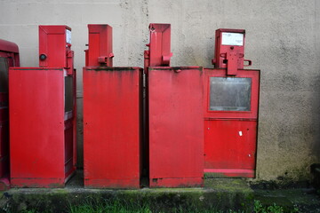 Bright red newspaper dispensers abandoned in alley.
