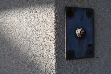 Metal cover plate on corner of concrete wall.