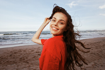 Fototapeta na wymiar Joyful Woman Dancing by the Sunny Sea in Red Beach Fashion - Carefree Summer Vibes