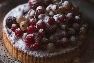 The cake with berries is sprinkled with powdered sugar