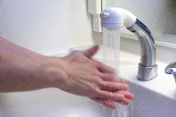 蛇口から流れる水で両手を洗う