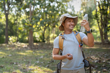 Traveler hiking man carrying a backpack on the back and walking in national park. man asian is rest by drink water