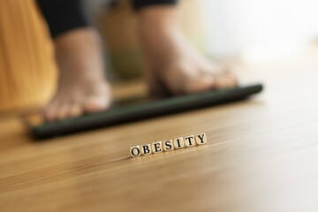 Obesity concept with weight scale and feet in background - 728967110