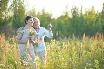 Naklejka na ściany i meble mom and daughter with flowers in the field