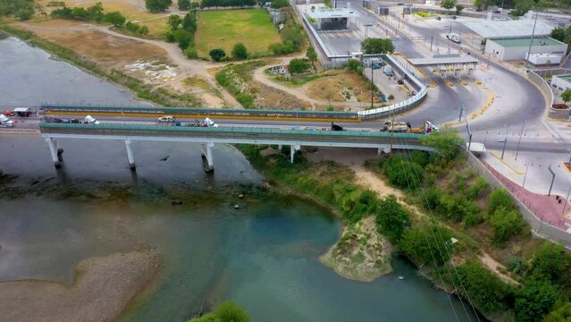 aerial footage of the International Bridge connecting Acuña, Mexico, and Del Rio, Texas. The video showcases the flow of cross-border commerce with 5 cargo trailers.