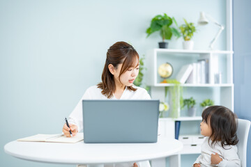 子供の面倒を見ながらパソコン作業をする母親
