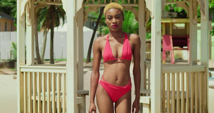 On the sun-kissed shores of the Caribbean, a girl with ebony skin enjoys the day in her red bikini.