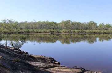 View of the Boyne River with water, trees and rocks at Boyne Island in Queensland, Australia